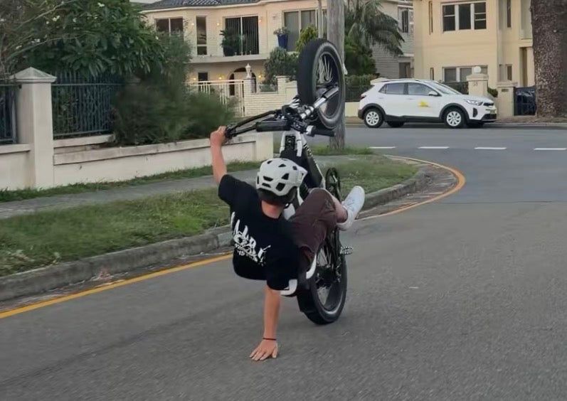 Rider pulling a wheelie on a PlugNPlay equipped e-bike